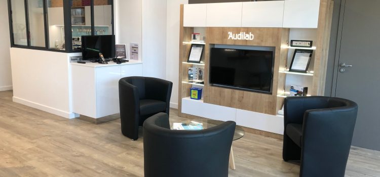 Vue intérieure moderne du centre auditif Audilab avec sièges confortables, bureau d'accueil et décoration épurée