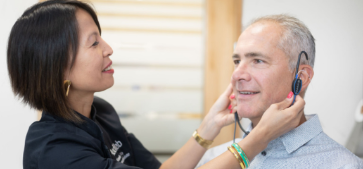Audioprothesiste audilab qui examine l'oreille d'un patient lors d'un bilan auditif.